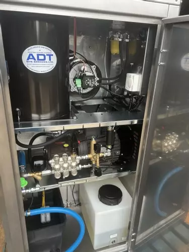 Internal view of a Nilfisk 400HS DTE system showing pump, burner, pipework, and chemical setup after installation and modifications. Clean, organised layout designed for reliability and ease of servicing.